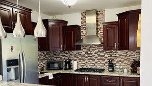 A modern kitchen with dark wooden cabinets, stainless steel appliances, and a granite countertop. - Your home away from home! (Cafemba)