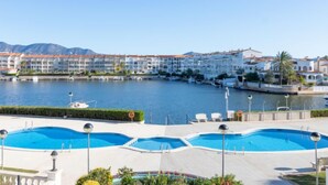 A coastal hotel with multiple swimming pools, a marina, and mountain views.