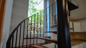 A staircase with a wooden handrail and black metal balusters leading to a kitchen area with white cabinets and a gas stove. - Modern apartment on the beautiful Croatia coast (Prižba)