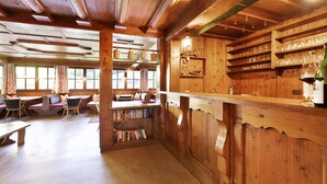 Un interior de madera con una zona de bar, estanterías y asientos.