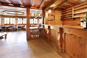 A wooden interior with a bar area, bookshelves, and seating. - Alpine Chalet Lacknerbrunn 25-30 persons with Mountain View (Mayrhofen)