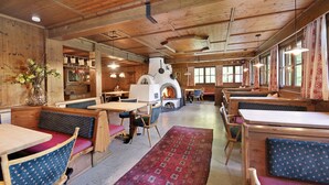 Un interior rústico con paredes de madera, una chimenea central y zonas de estar.