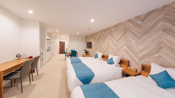 A hotel room with two beds, a desk, and a chair.