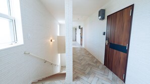 A modern interior with white brick walls, a wooden door, and a herringbone-patterned floor.