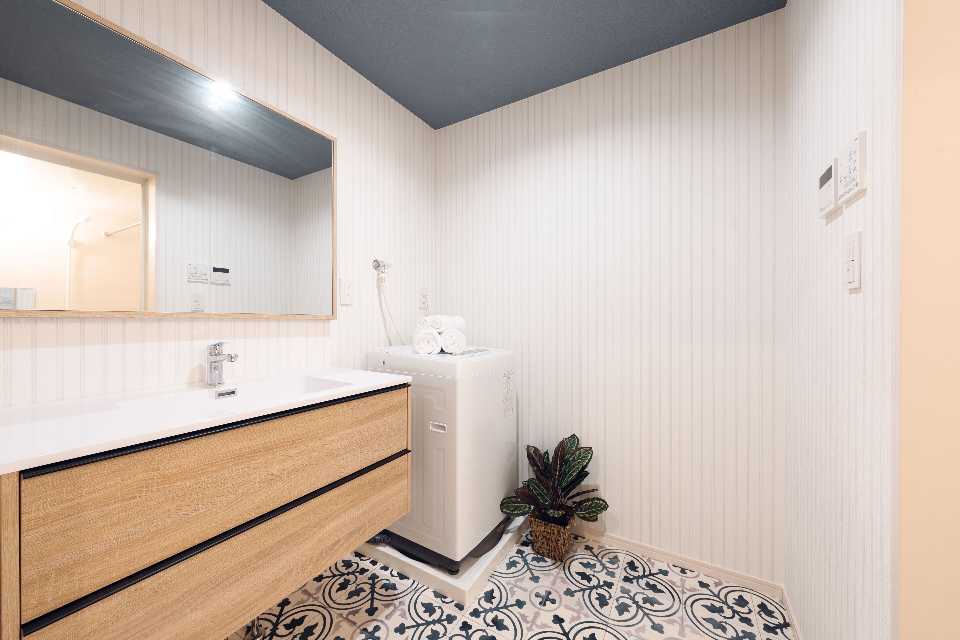 Un baño moderno con un lavamanos blanco, tocador de madera y un espejo grande.