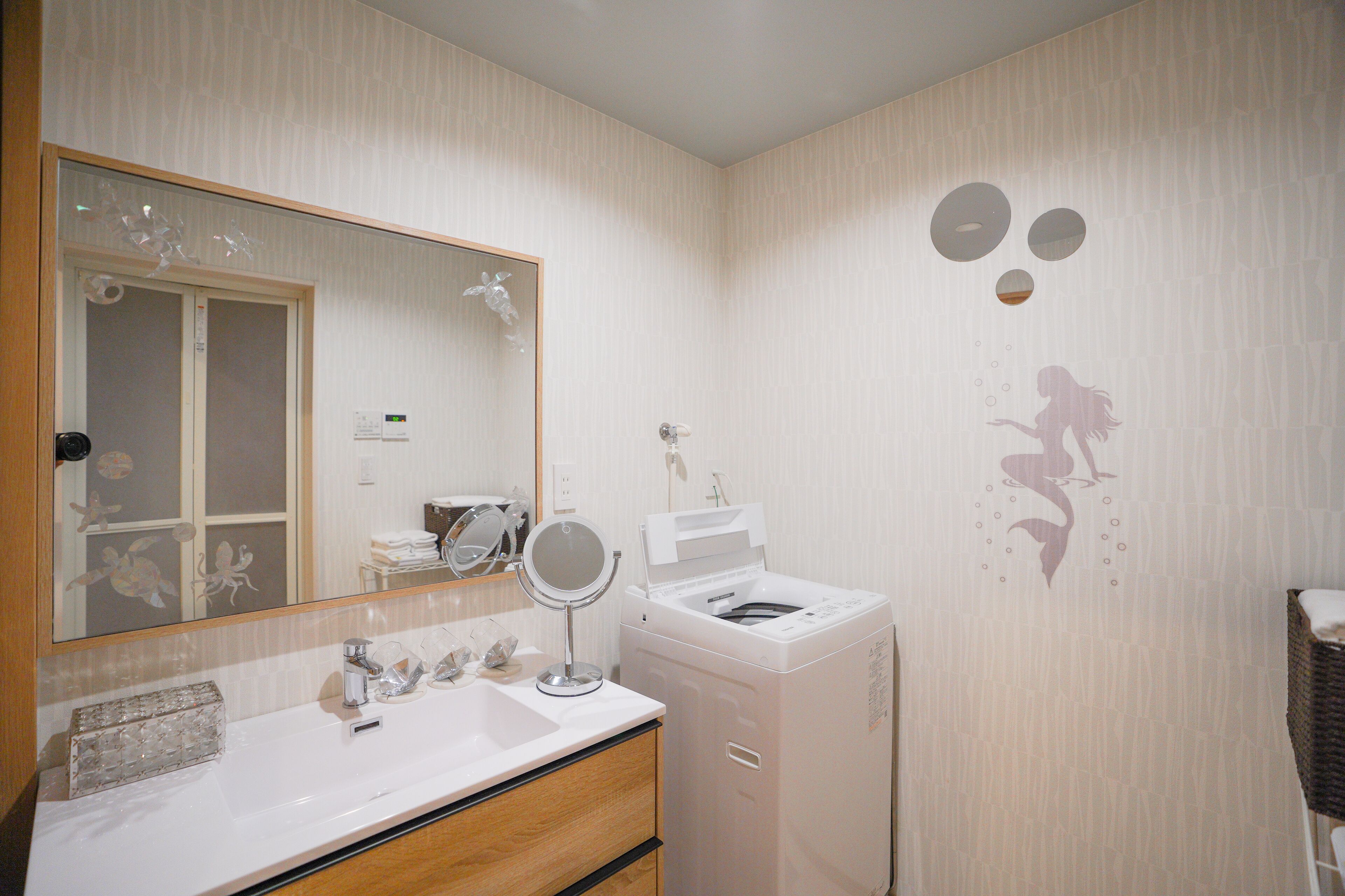 Une salle de bain équipée d’un lavabo, d’un miroir et d’un lave-linge.