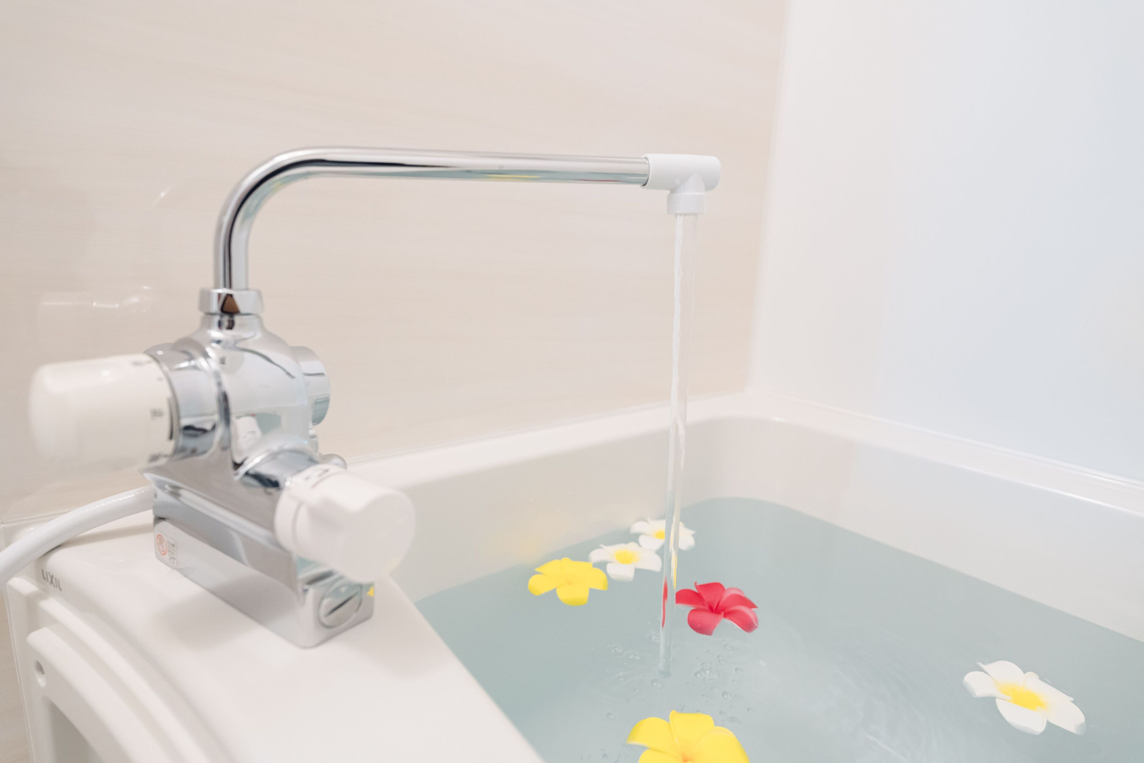 Una bañera con un grifo y flores flotando en el agua.
