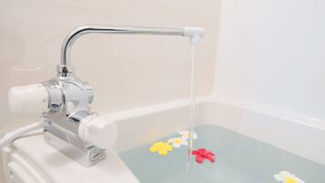 Una bañera con un grifo y flores flotando en el agua.
