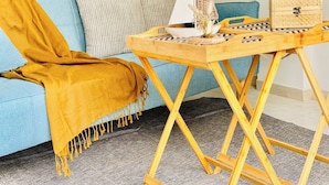 A cozy living room with a blue sofa, a wooden coffee table, and a mustard-colored throw blanket.