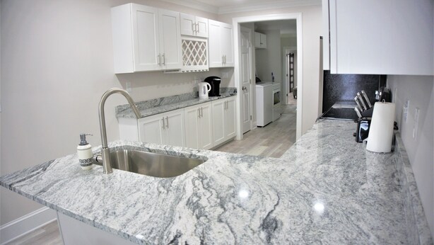 Una cocina moderna con armarios blancos, encimera de granito y electrodomésticos de acero inoxidable.