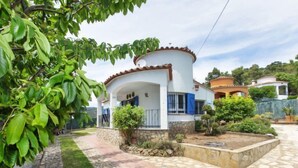 A two-story house with a stone pathway leading to the entrance, surrounded by greenery and a small garden. - Vacation home Ami by Interhome (Calonge)