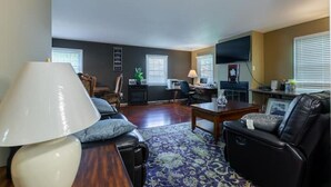 A living room with a sofa, a coffee table, a TV, and a desk with a computer. - Single family dream in the hearth of FAIRFAX VA (Fairfax)