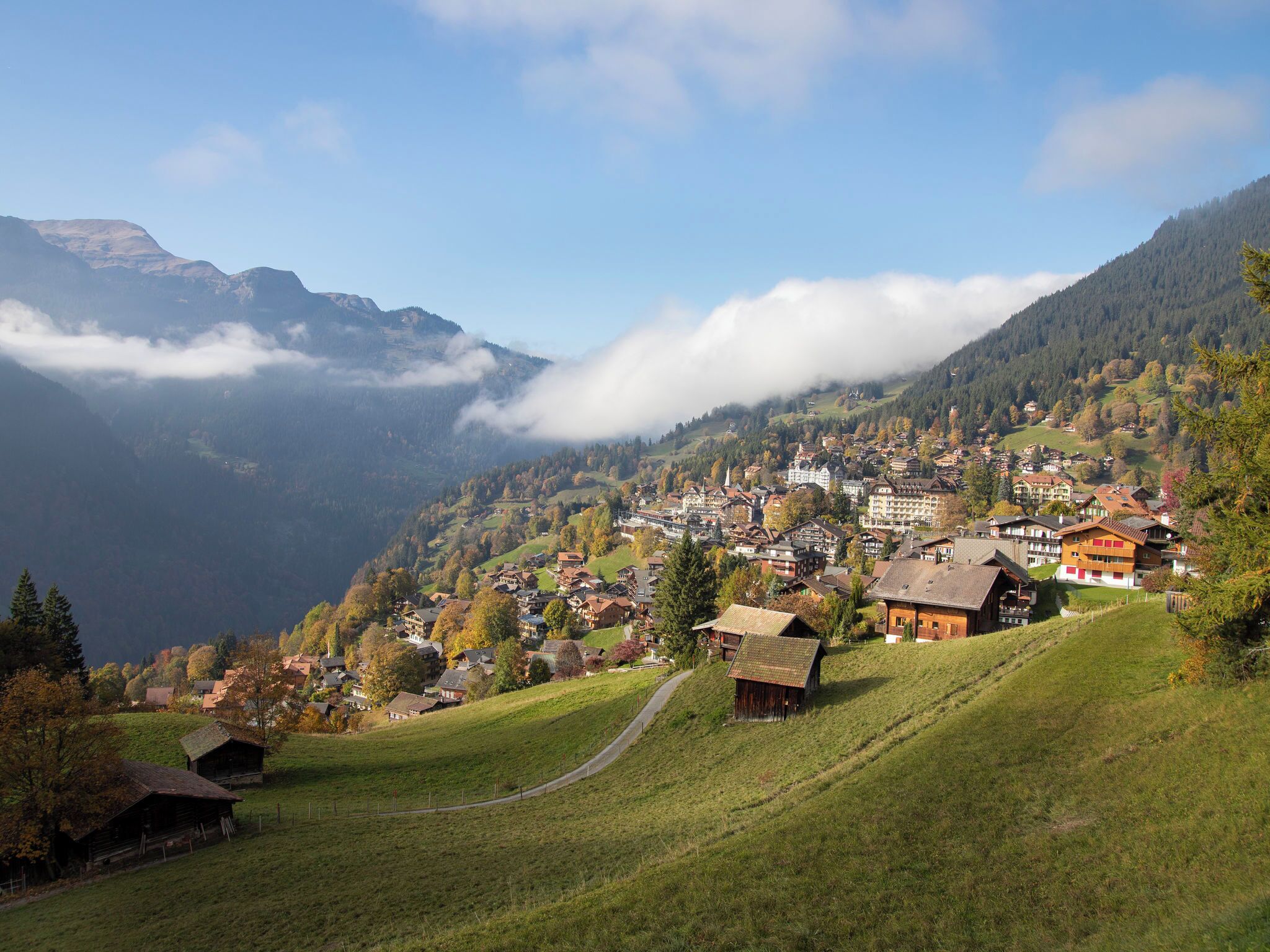 A mountainous village with traditional houses, a winding road, and a valley below.
