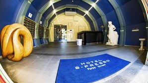 A hotel lobby with a blue carpet, a statue, and a wooden sculpture. - S-Presso Namba Parks Street  (Osaka)
