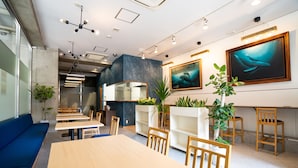 A modern restaurant with a long wooden table, blue seating, and potted plants. - S-Presso Namba Parks Street  (Osaka)