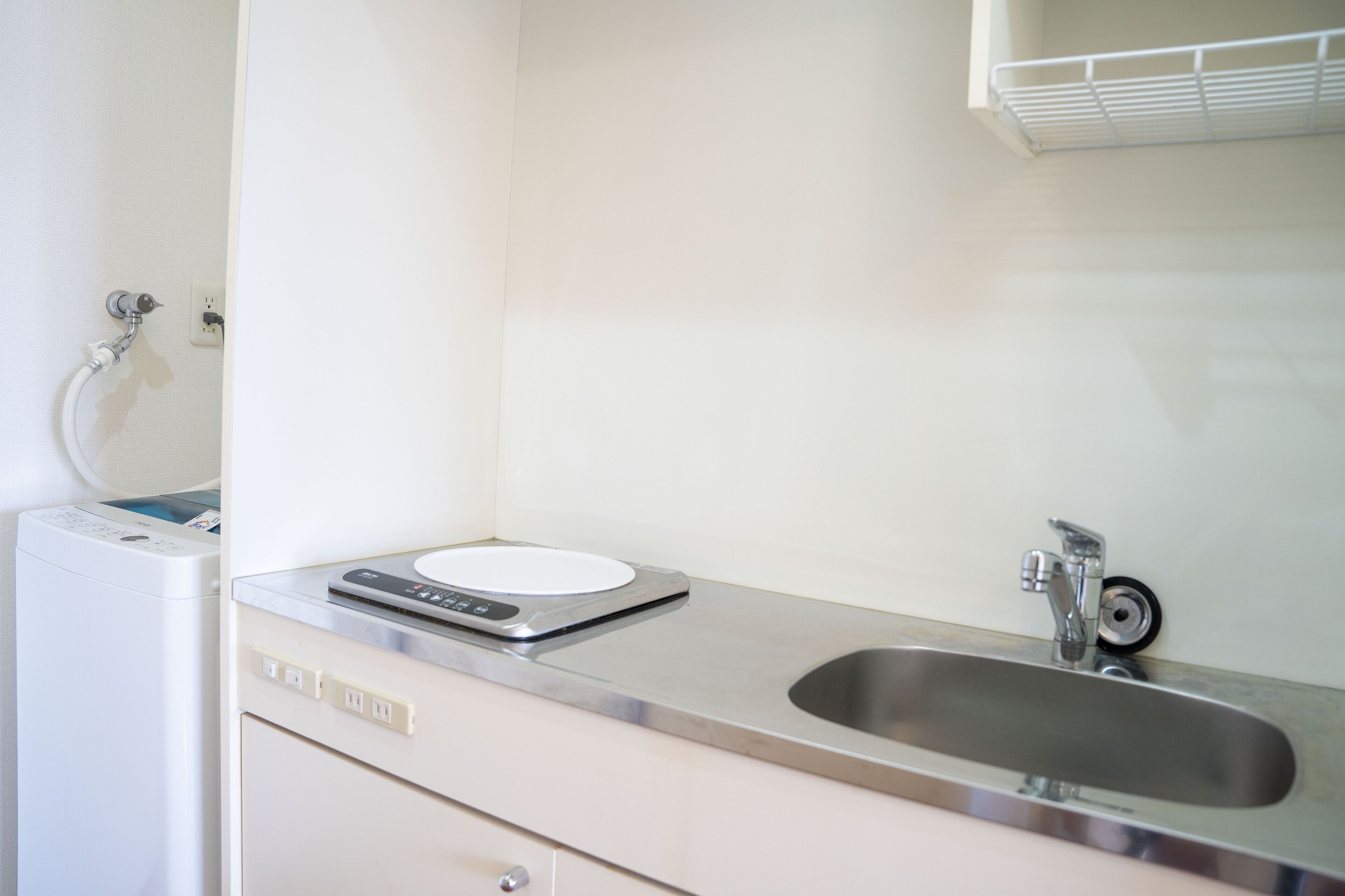 A kitchen with a stainless steel sink, a built-in scale, and a white washing machine.