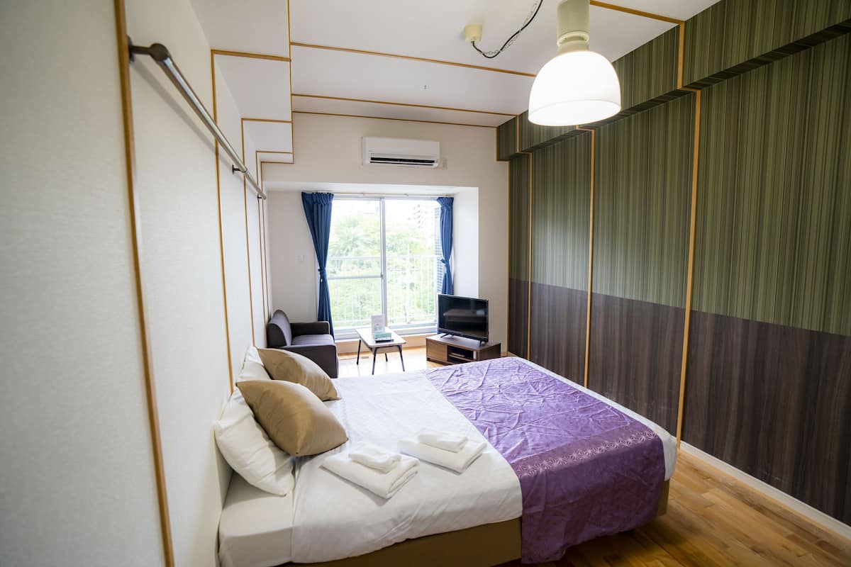 A hotel room with a bed, a desk, a chair, and a television.