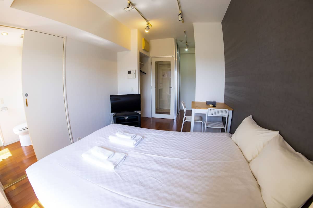 A hotel room with a large bed, a desk, a chair, and a television.