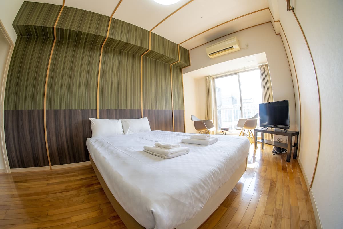 A hotel room with a large bed, a television, and a seating area with chairs.
