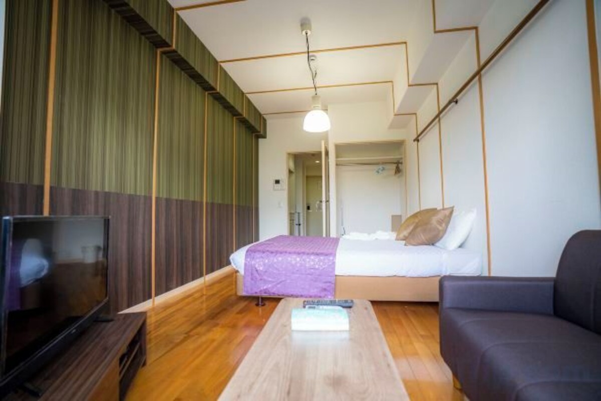 A hotel room with a bed, a TV, a wooden coffee table, and a sofa.