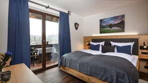 A bedroom with a large bed, a wooden headboard, a view of a balcony, and a painting on the wall. - 3/4/5/7 Gamsbleame for 1-2 pers., 21 m2 (Bischofswiesen)