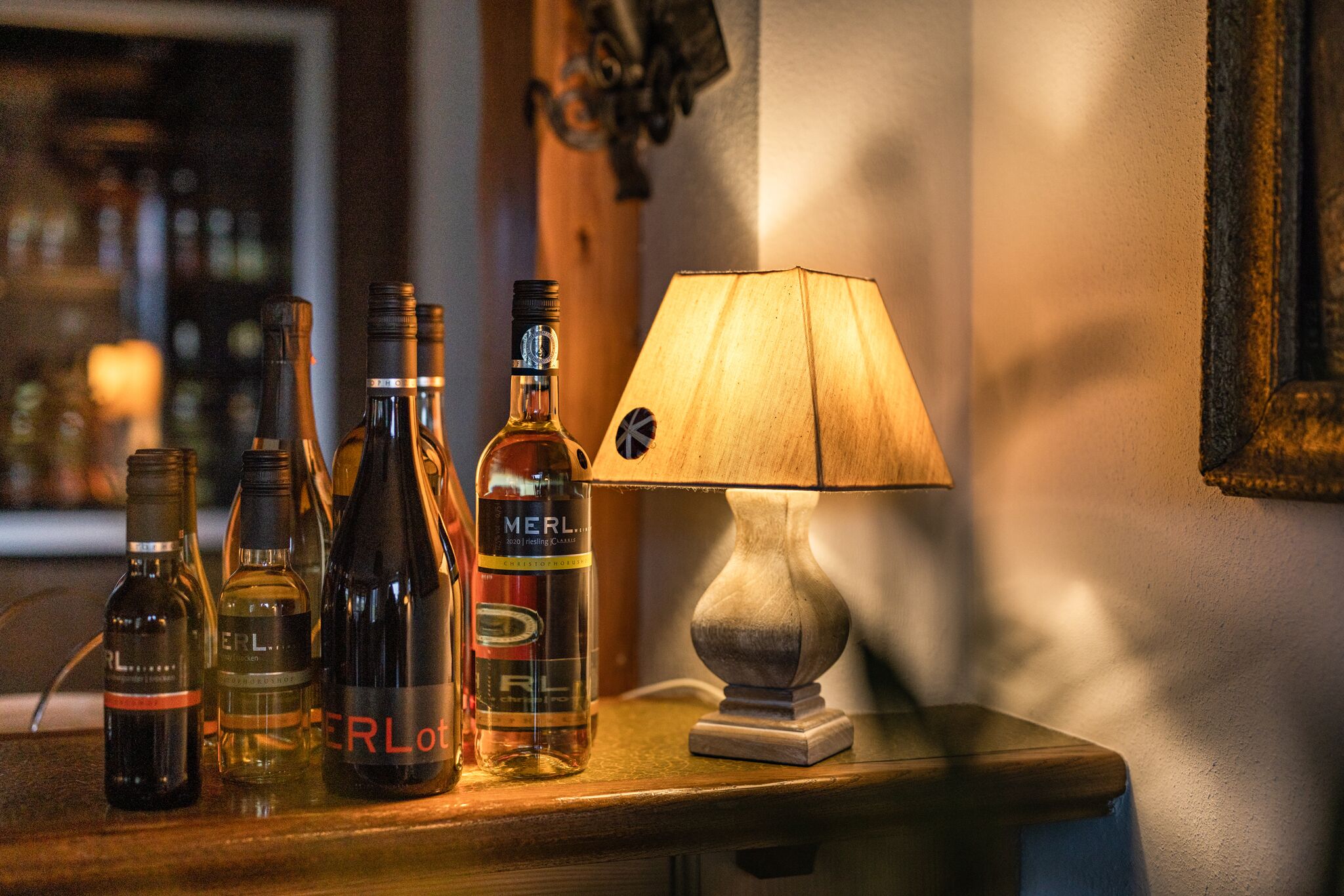 A bar area with bottles of liquor and a lamp on a wooden counter.