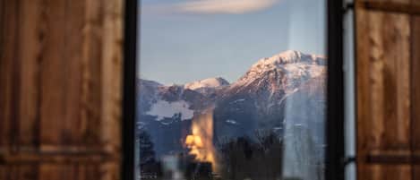 Una finestra con vista su montagne innevate e una fonte di luce calda in lontananza.