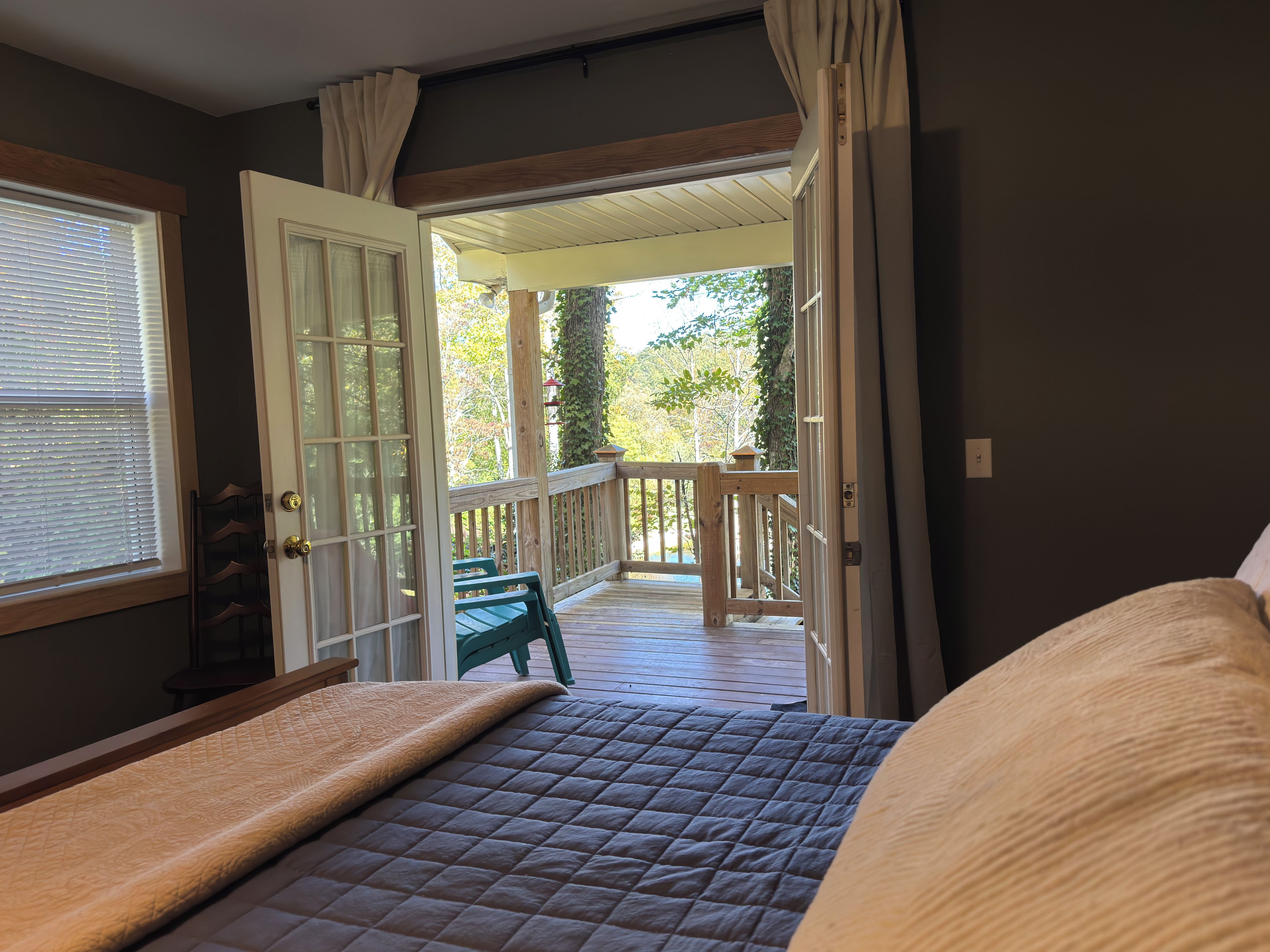 Un dormitorio con cama, vistas al exterior y una terraza de madera.