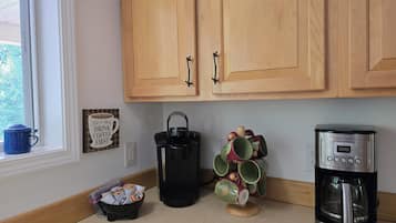 A kitchen with wooden cabinets, a coffee maker, a kettle, and a mug holder.