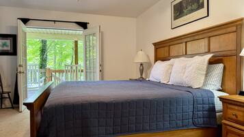 Un dormitorio con una cama grande, una mesita de noche, un cabecero de madera, un ventilador de techo y vistas al exterior.