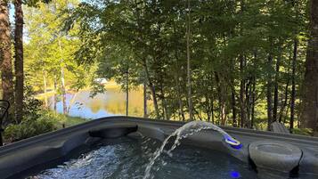 Jacuzzi con agua en movimiento, rodeado de árboles y vistas al lago.