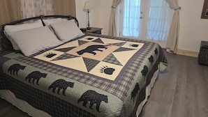 Een slaapkamer met een bed, een nachtkastje, een lamp en een raam met gordijnen.