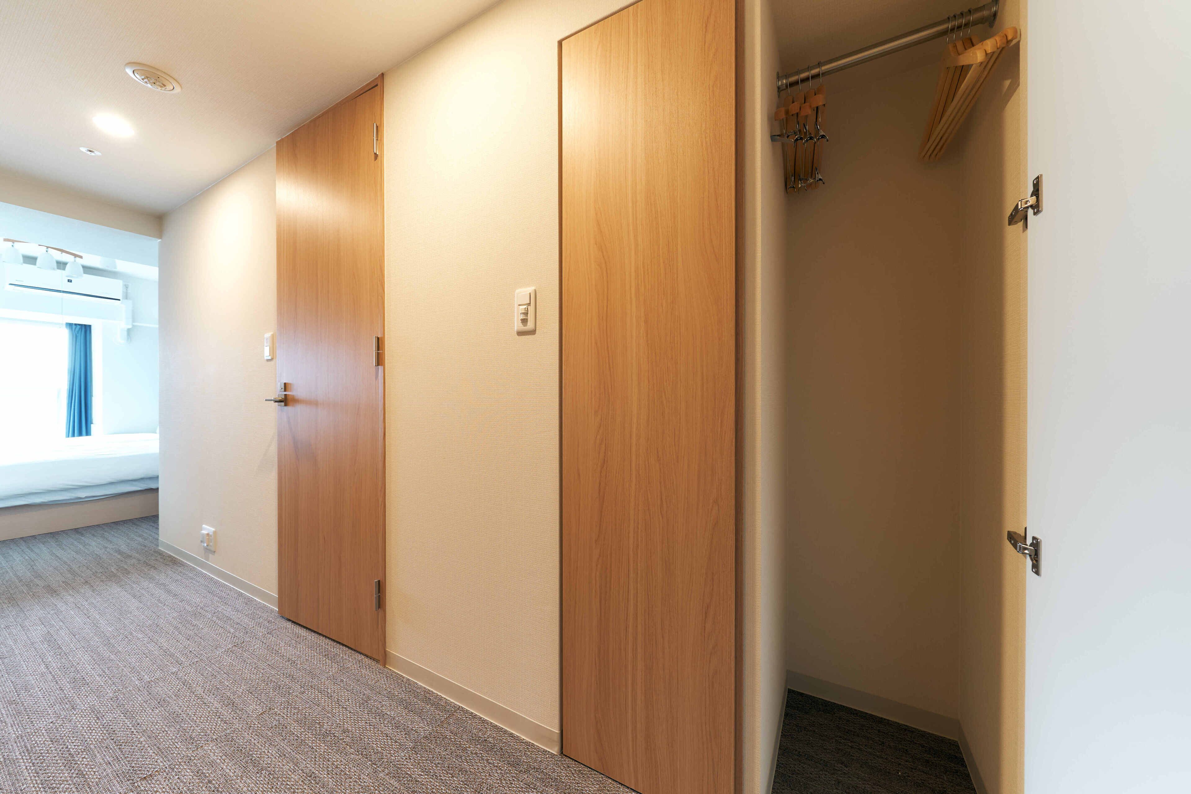 A hallway with wooden doors, a window with blue curtains, and a ceiling with recessed lighting.