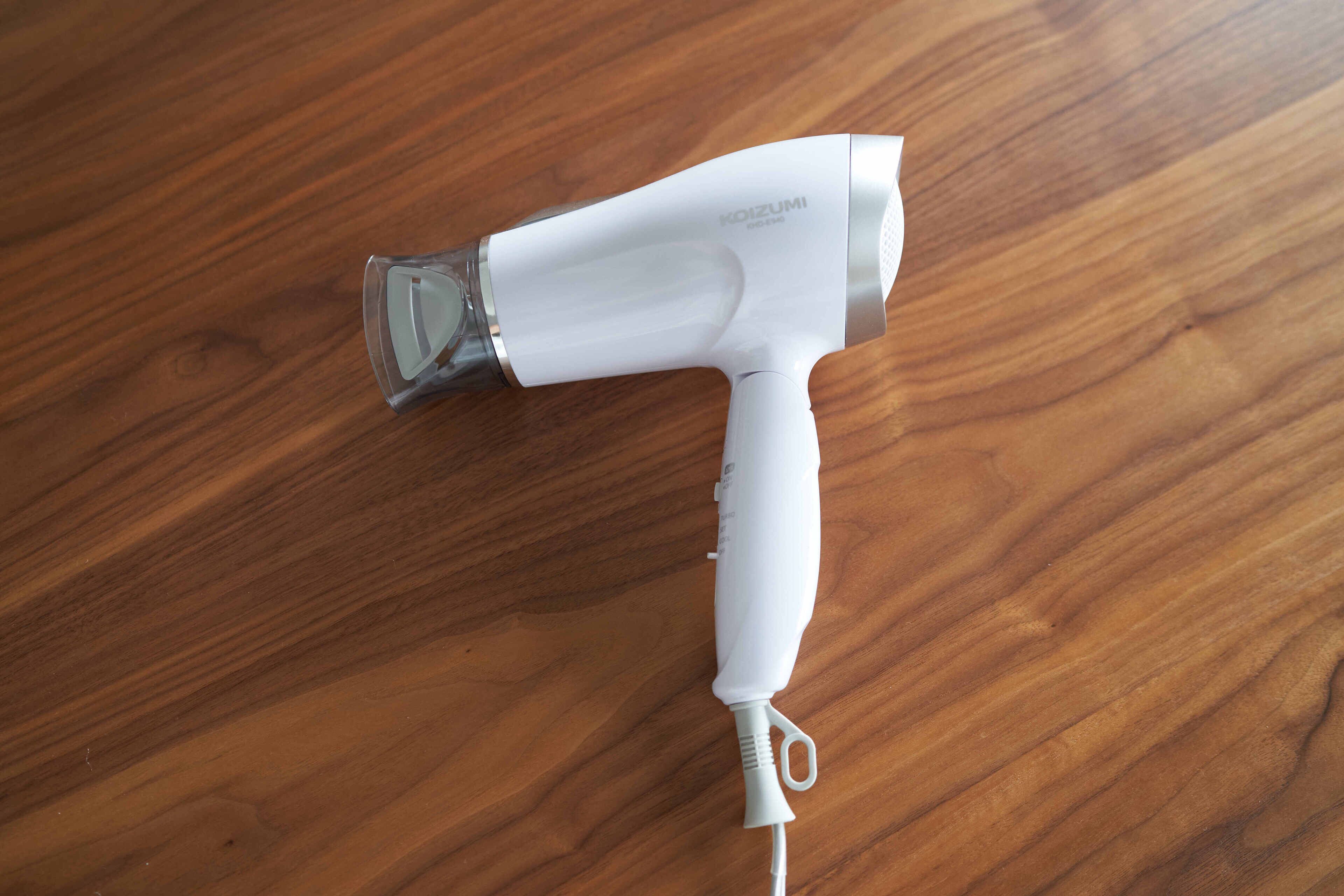 A white hair dryer with a transparent water bottle on a wooden surface.