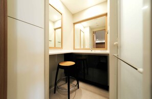 A compact kitchen with a single stool, a built-in dishwasher, and a mirror above the counter. - STAYAT OSAKA SHINSAIBASHI east (Osaka)