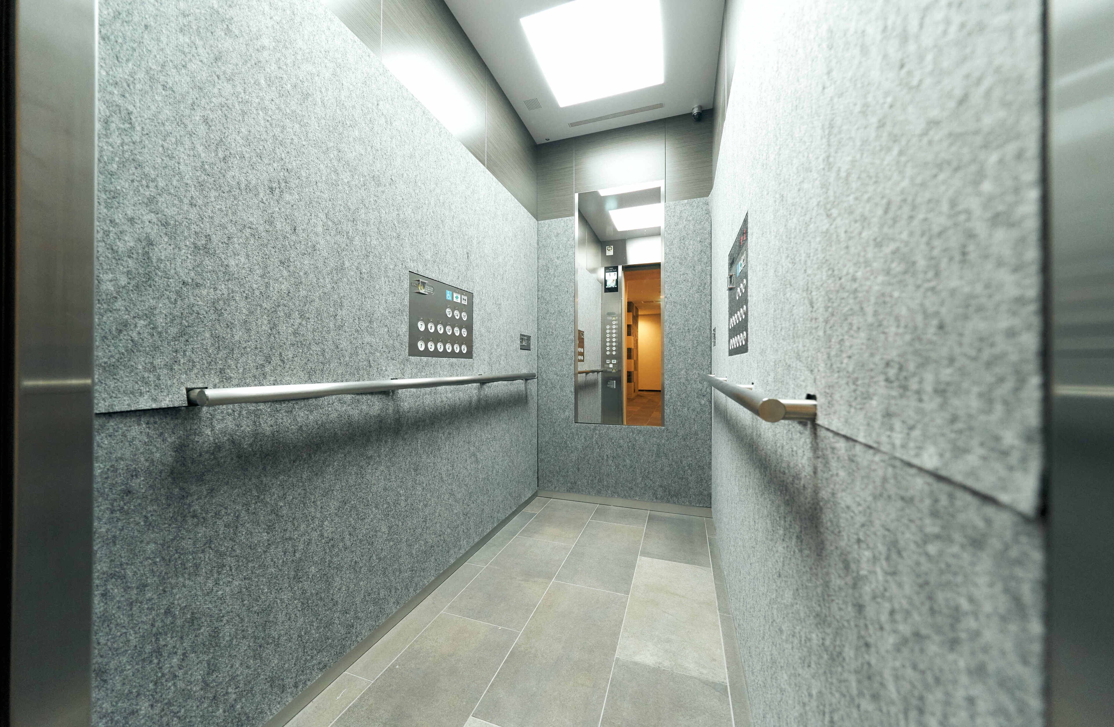 A corridor with grey walls, a handrail, and a sign with floor numbers.