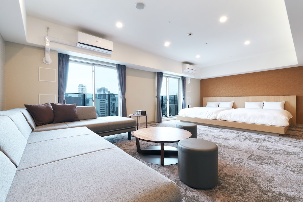 A modern hotel room with a large bed, a sofa, a small table, and a round coffee table.