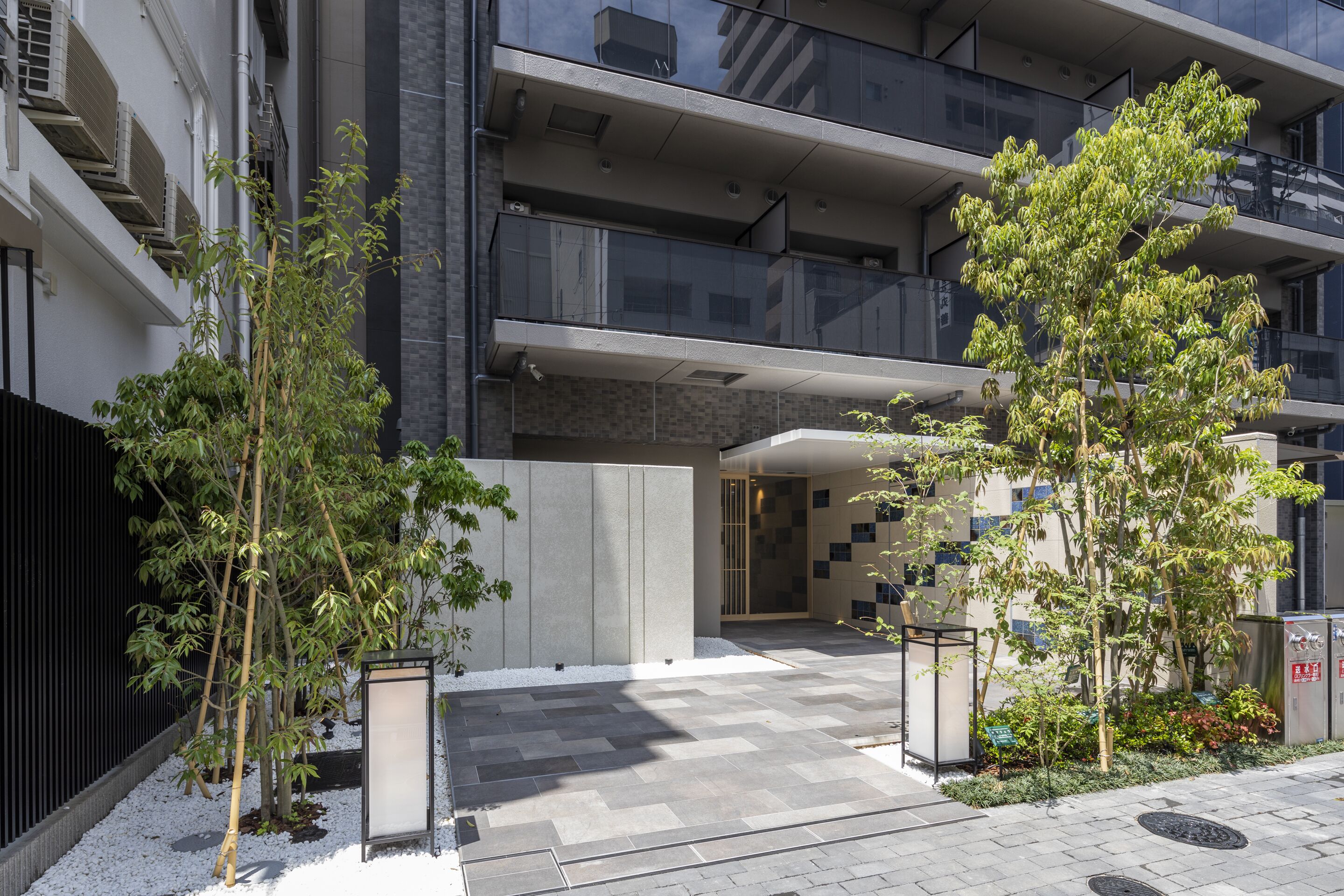 A modern building with a courtyard, featuring a mix of concrete and glass elements, and a few trees.