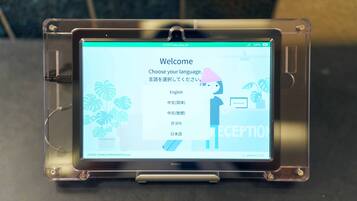 A digital kiosk with a touchscreen interface displaying a language selection menu.