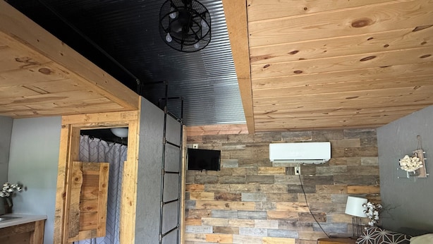 A room with a wooden ceiling, a stone wall, a bed, a desk, and a ladder. - Cottonwood Cabin - Cozy Retreat w/ Fire Pit & 150 Acres (Gridley)