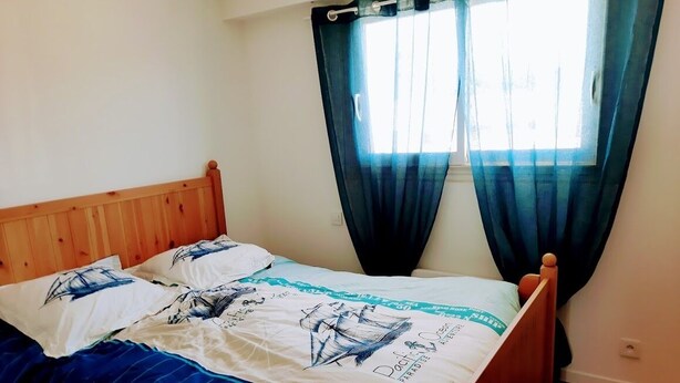 Una cama con cabecera de madera, edredón y almohadas a cuadros en azul y blanco.