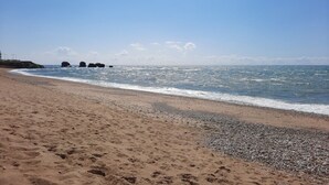 Una playa con orilla pedregosa y mar tranquilo.