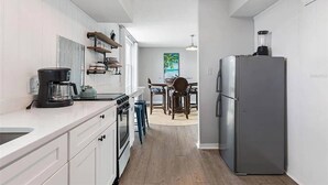 Eine moderne Küche mit weißen Schränken, einem Edelstahl-Kühlschrank und einer Kaffeemaschine auf der Arbeitsfläche.