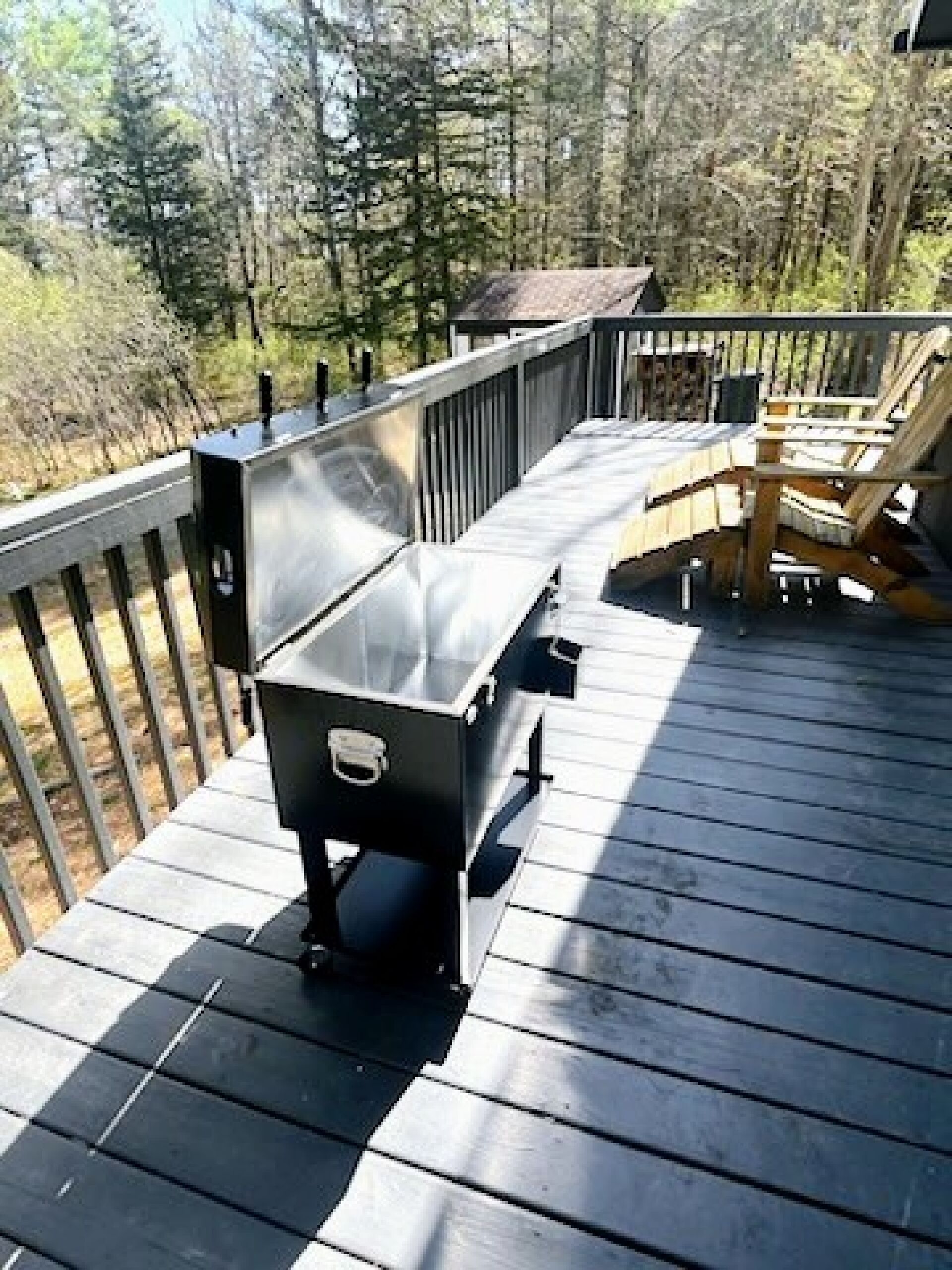 Una terraza de madera con una parrilla y mobiliario exterior.
