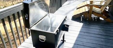 Una terraza de madera con una parrilla y mobiliario exterior.