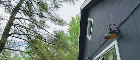 A deck with a grill and chairs, overlooking a forested area.