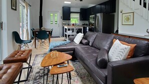 En moderne stue med en mørk lædersofa, et træsofabord og en tæppe med et mønster.