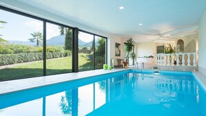 Una piscina con vista sulle montagne, un balcone con ringhiera e una pianta in vaso.