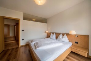 Une chambre d’hôtel avec un lit en bois, des tables de chevet, un miroir et une porte donnant sur une salle de bain.