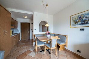 Une cuisine moderne avec des meubles en bois, une table à manger avec des chaises et un luminaire suspendu.